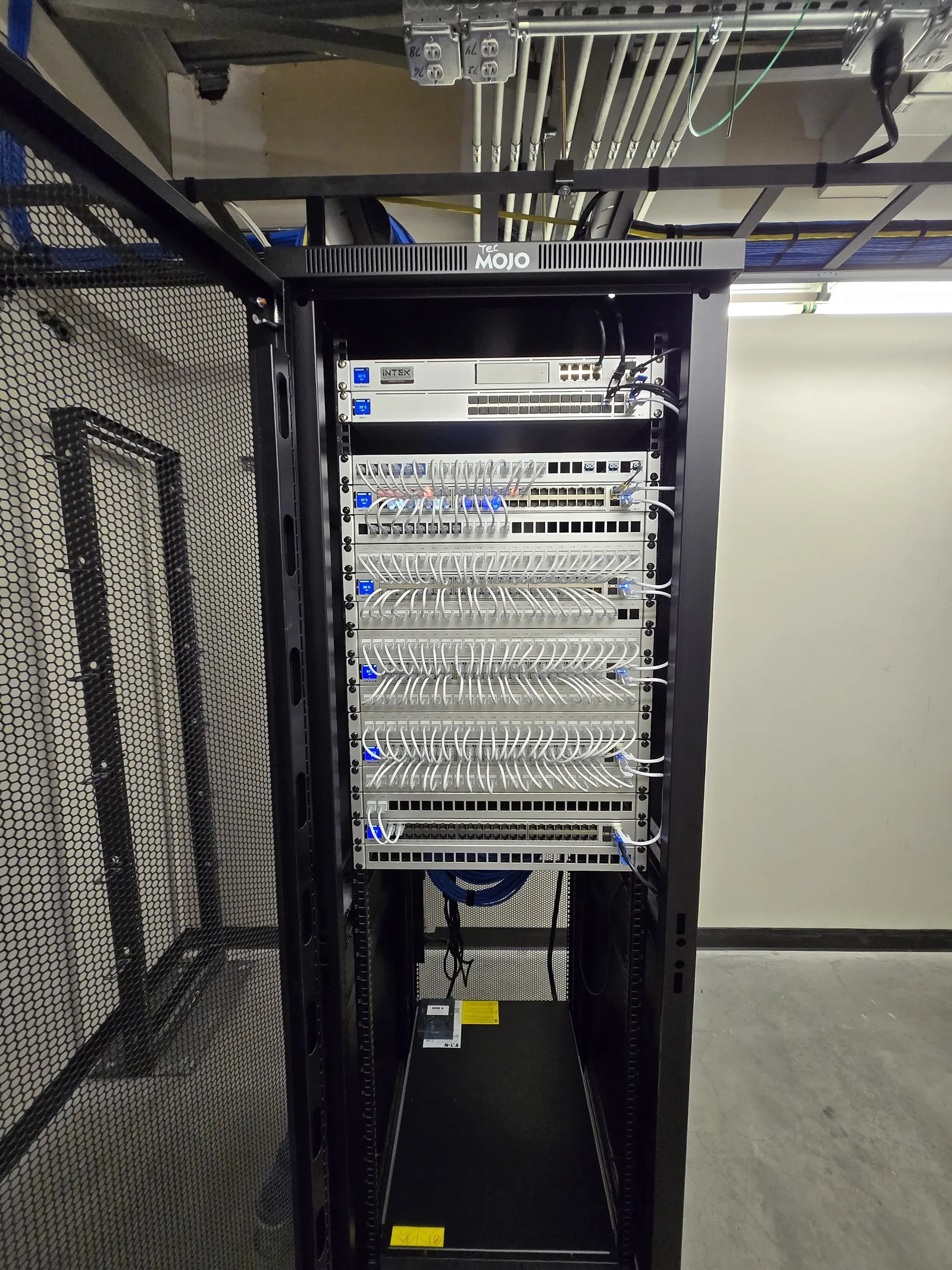 Full-height rack build with organized cabling in a dedicated network room by INTEK