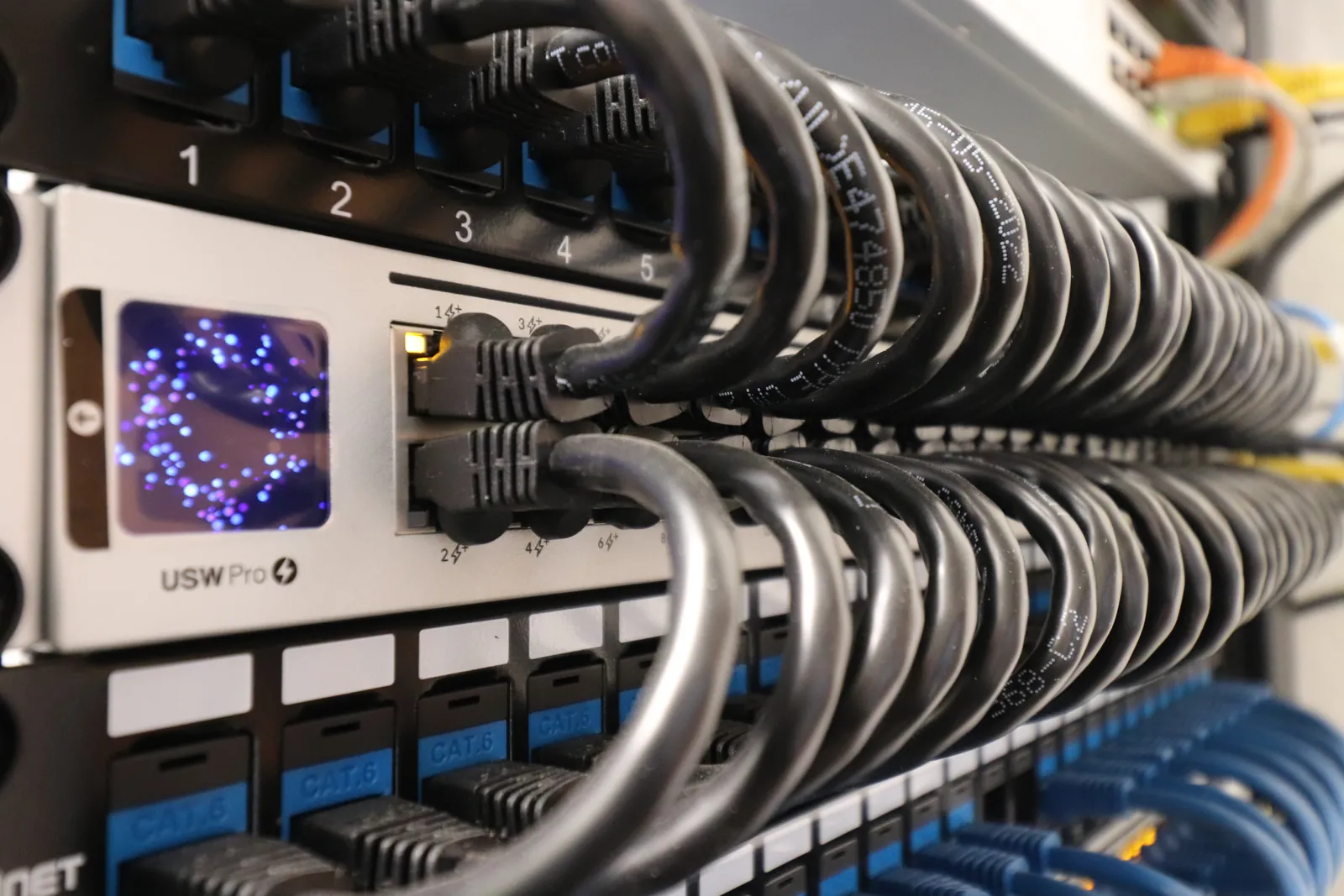 UniFi USW Pro switch with status display and dressed patch cables installed by INTEK